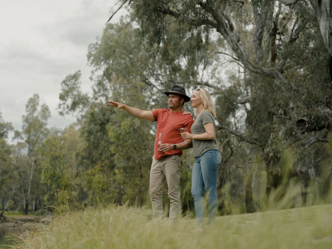A man and woman stand on the banks of the Murray River