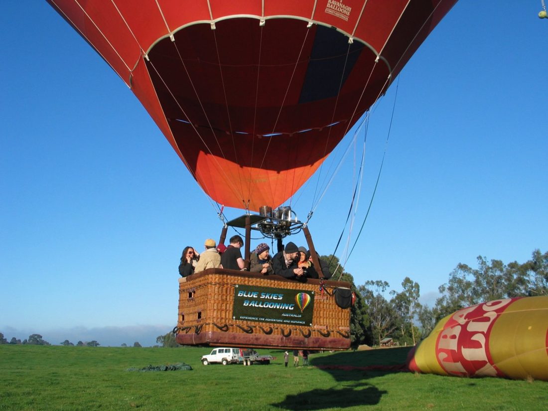 Airborne and drifting gently across the paddock while another balloon is inflating